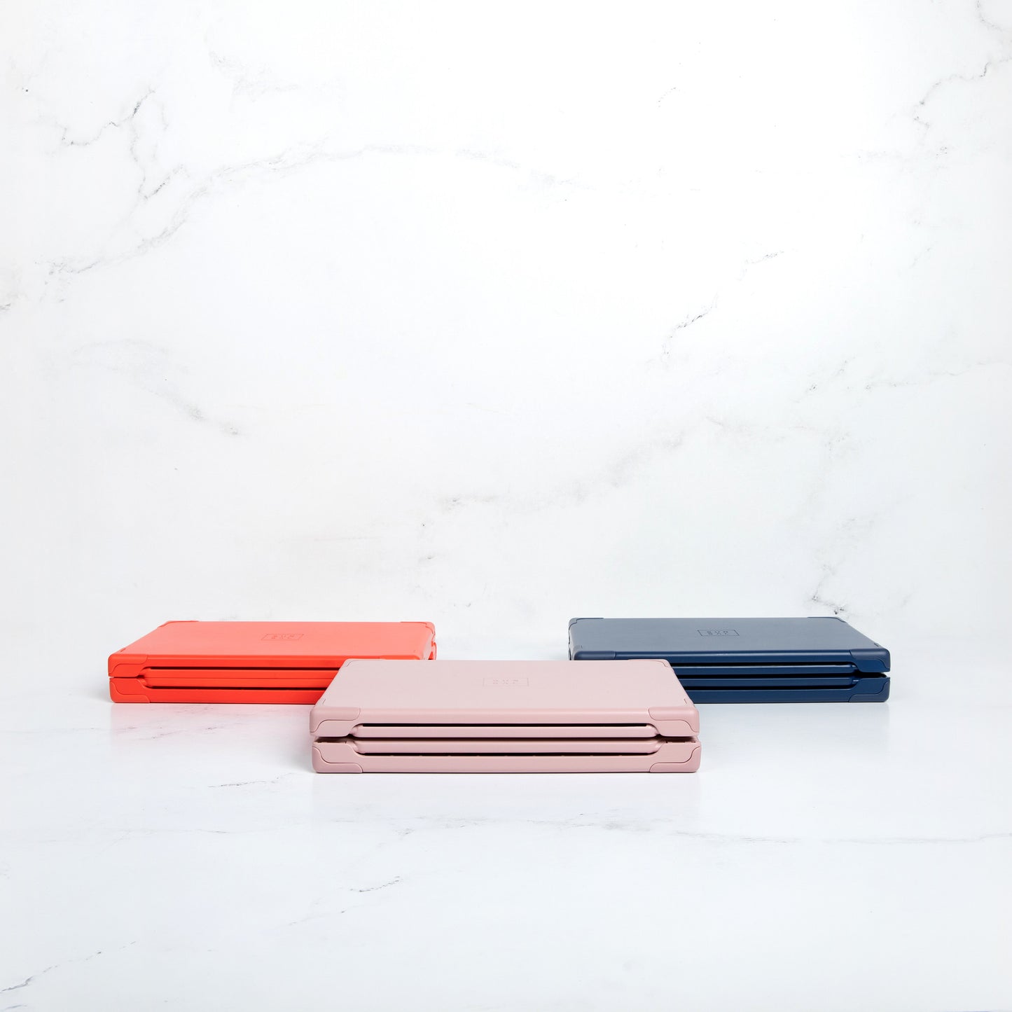 Sunsal yoga blocks in Rosewood, Coral, and Navy displayed in their collapsed form, showcasing portability and modern design