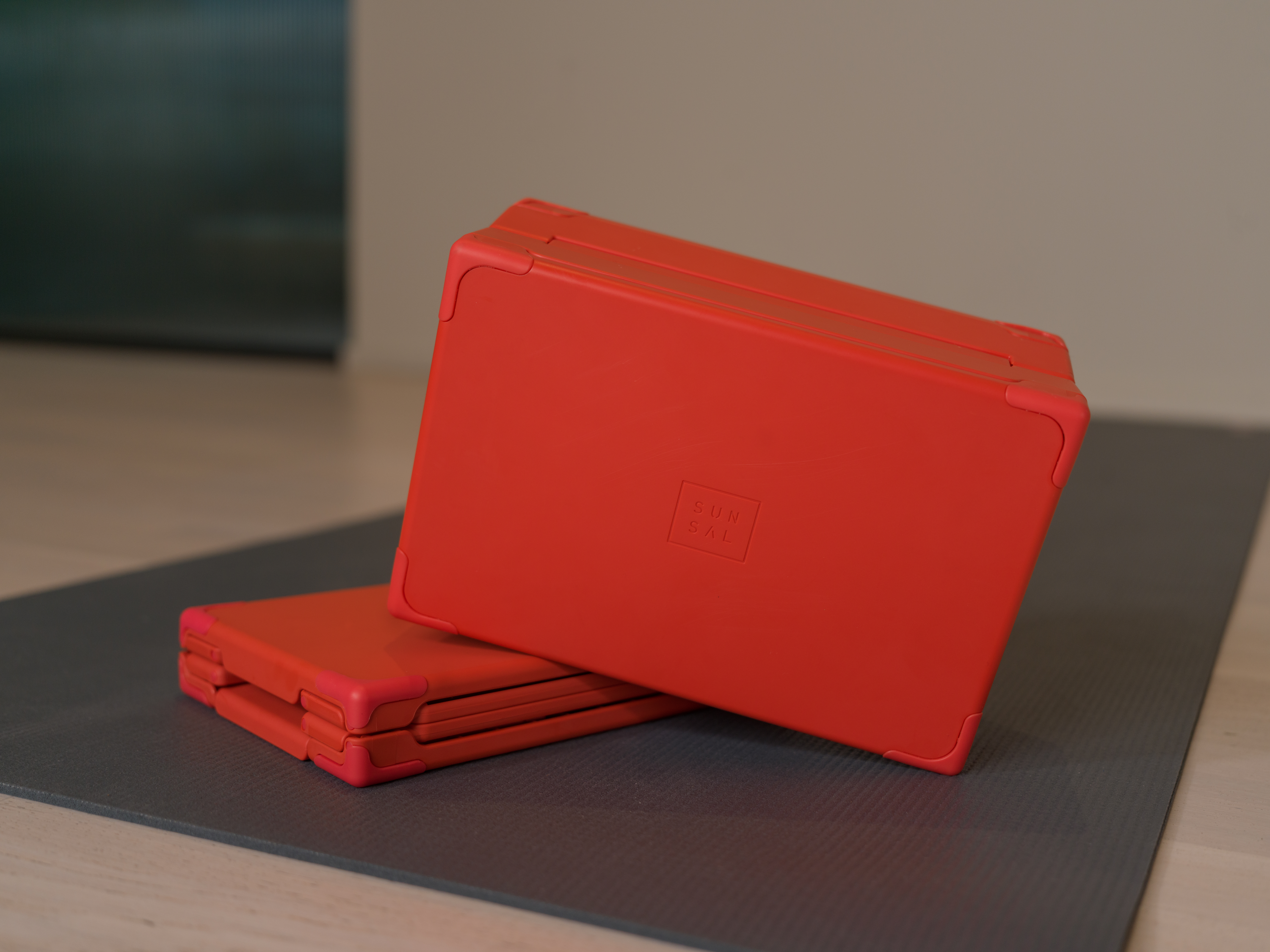Coral SUNSAL yoga block shown expanded for practice and collapsed flat for travel.