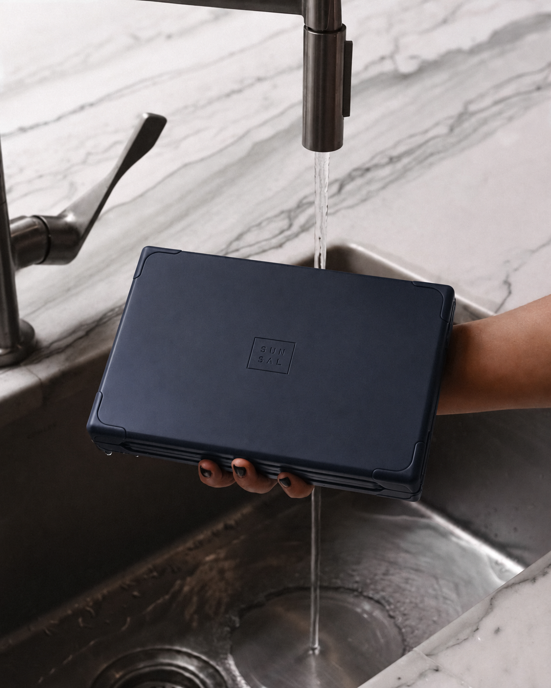 Navy SUNSAL yoga block under running water in a sink, showcasing easy-to-clean materials