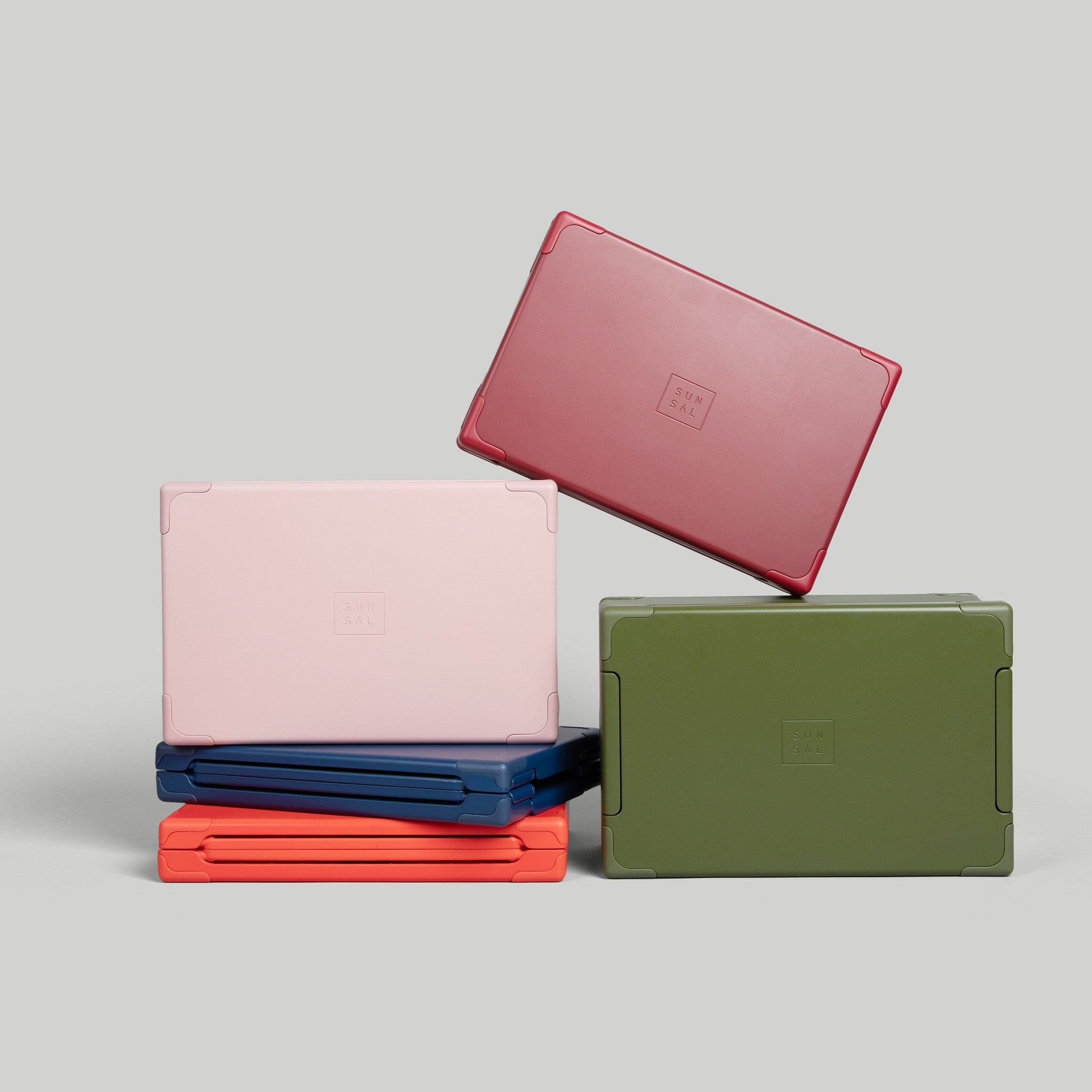 Set of Sunsal collapsible yoga blocks in Navy, Rosewood, Sage Green, Burgundy, and Coral, shown expanded and collapsed, on a light grey background