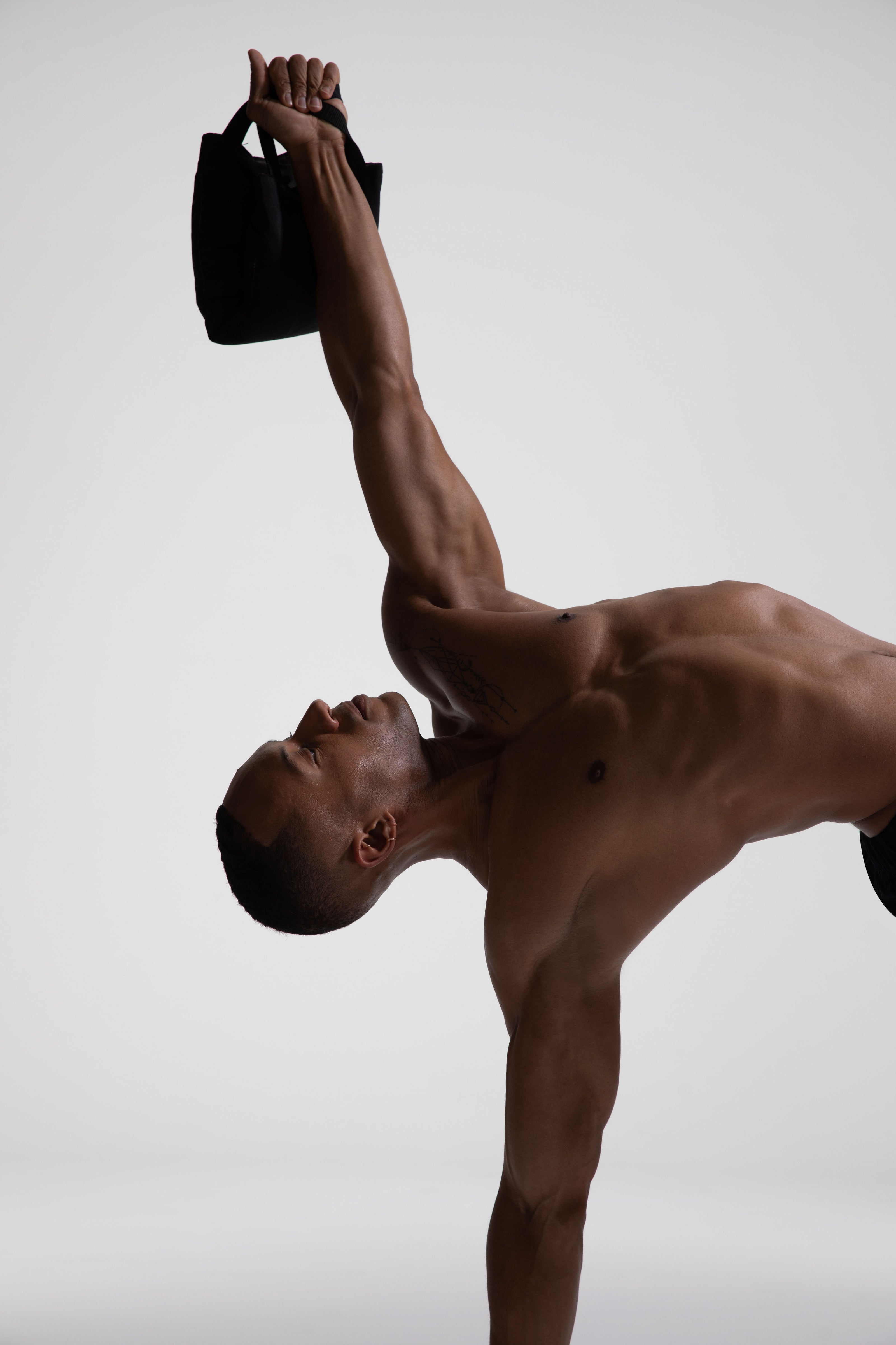 Yogi performing a side plank while lifting a Sunsal yoga block, showcasing strength and balance in an advanced pose