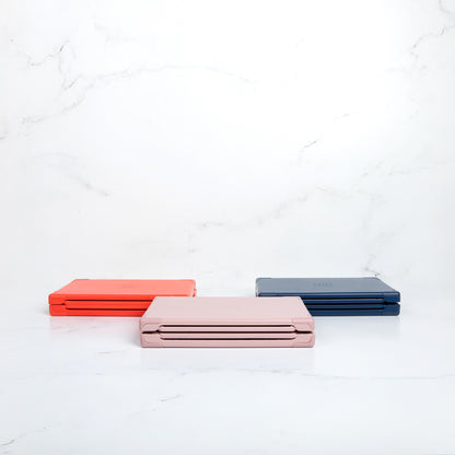 Sunsal yoga blocks in Rosewood, Coral, and Navy displayed in their collapsed form, showcasing portability and modern design